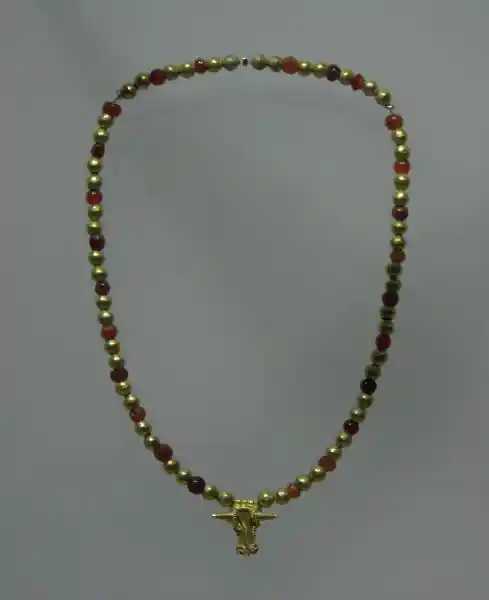 A gold necklace with red and gold beads and bullhead pendant A gold necklace with red and gold beads and bullhead pendant